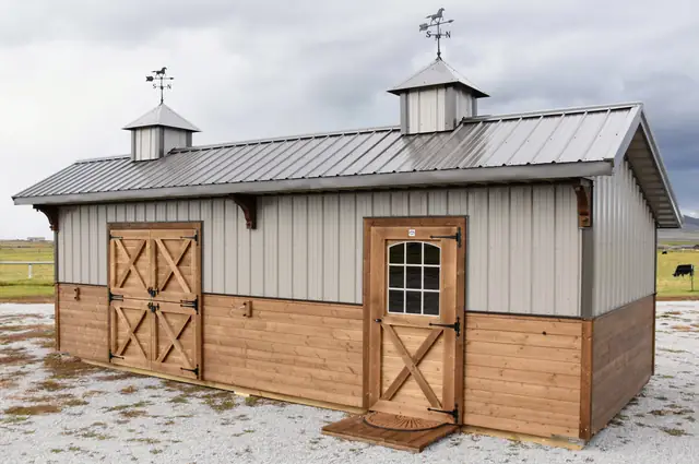 Horse barn end with a pair of cross-braced stained doors, a windowed door and two cupolas